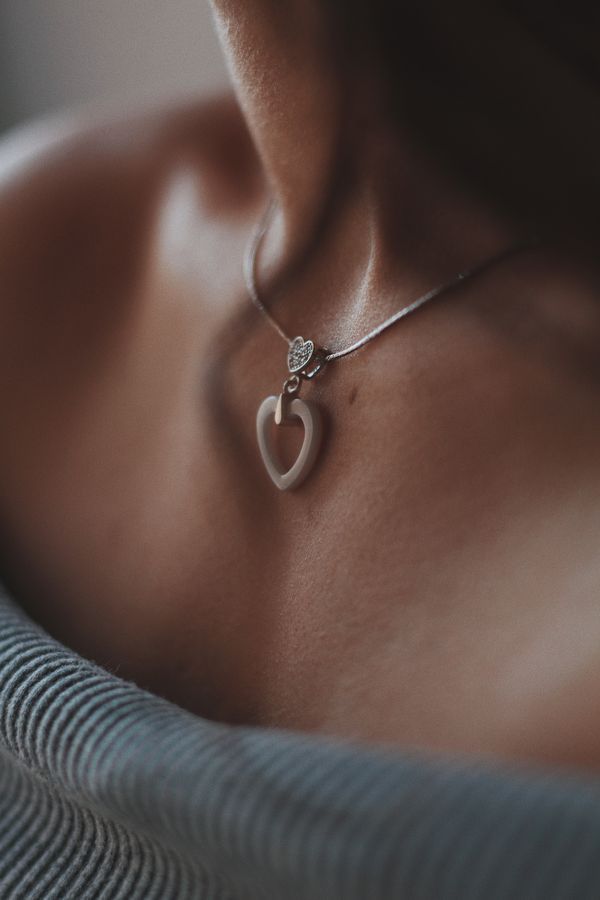 Closeup shot of a female wearing a beautiful silver necklace with a pendant